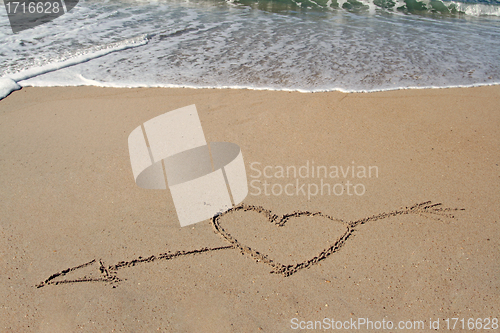 Image of handwritten heart on sand with wave approaching