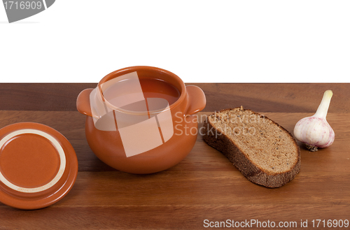 Image of Soup in ceramic pot with bread and garlic