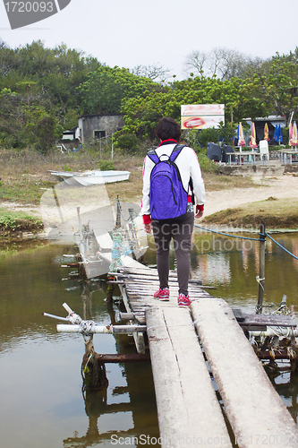 Image of Asian woman walking along a wooden bridge