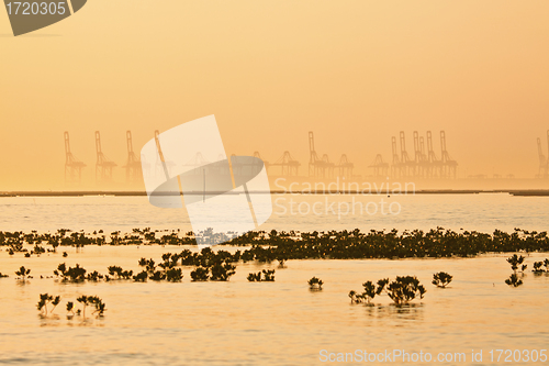 Image of Industrial ship and factory silhouetted at sunset 