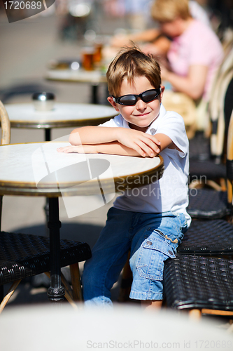 Image of Boy sitting in outdoor cafe 