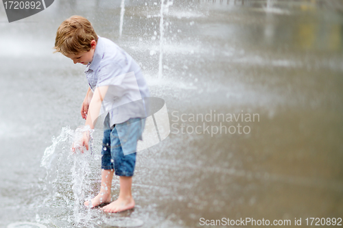 Image of Cute little boy playing with water outdoors