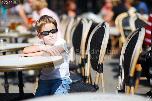 Image of Cute boy sitting in outdoor cafe