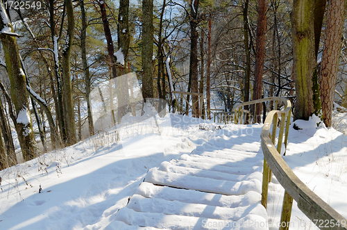 Image of Wooden snowy oak staircase with handrail on steep hill in winter 