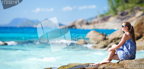 Image of Young woman relaxing on rocky coast