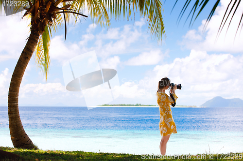 Image of Young woman taking photos at beach