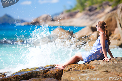 Image of Young woman relaxing on rocky coast