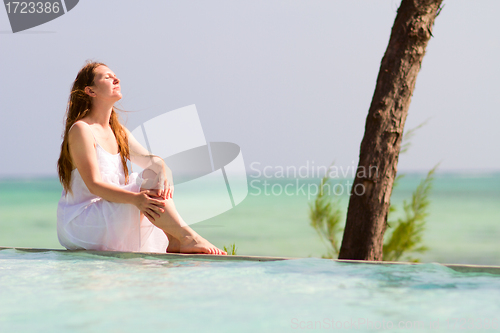 Image of Woman relaxing by swimming pool