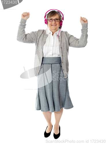 Image of Cheerful aged woman enjoying music