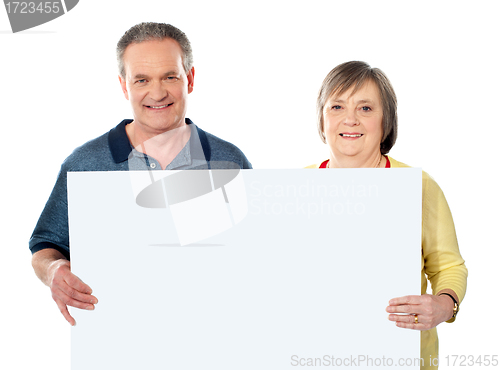 Image of Smiling aged couple holding blank white poster