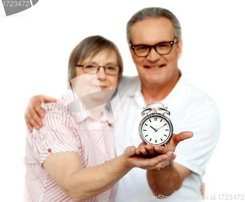 Image of Aged couple with alarm clock on plam