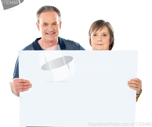 Image of Smiling aged couple displaying blank banner