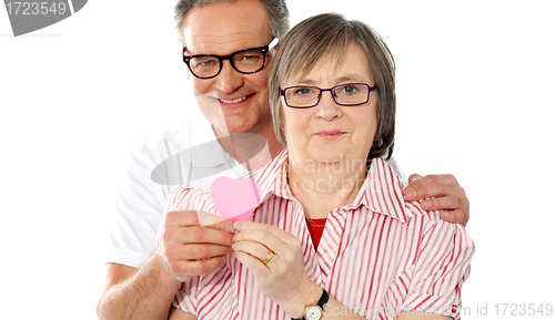 Image of Matured smiling couple holding paper heart