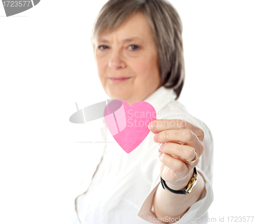 Image of Focus on pink paper heart. Aged woman holding it