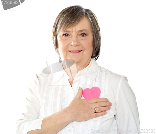 Image of Mature woman holding her paper heart close to body