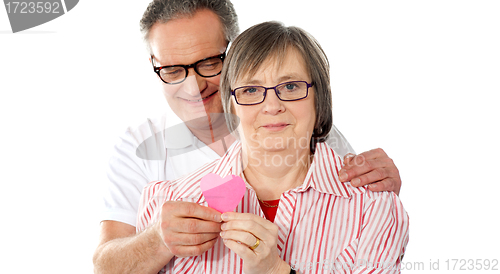 Image of Old couple facing camera with focus on paper heart