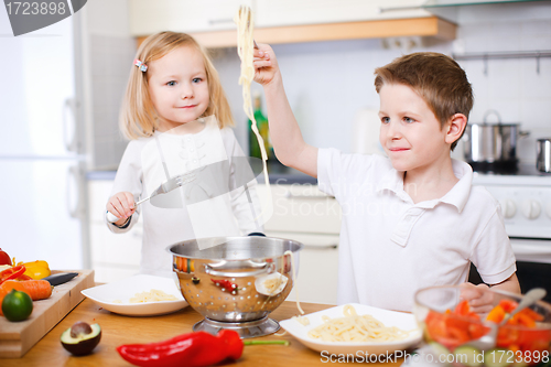 Image of Two kids eating spaghetti