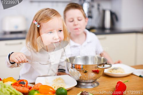 Image of Two kids eating spaghetti