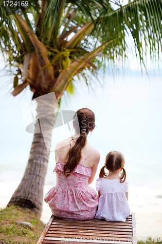 Image of Mother and daughter sitting under palm