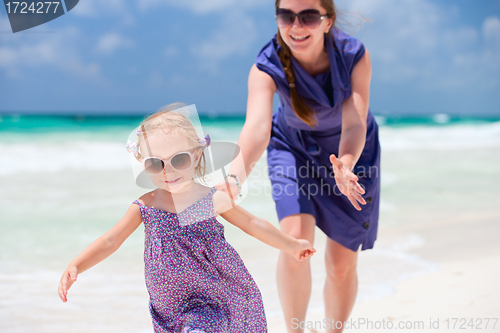 Image of Mother and daughter running at beach