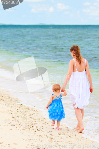 Image of Mother and baby walking along tropical beach