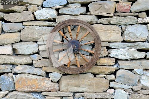 Image of Vintage Spinning Wheel on Stone Wall