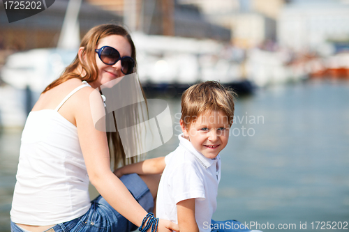 Image of Mother and son sitting on jetty in city center