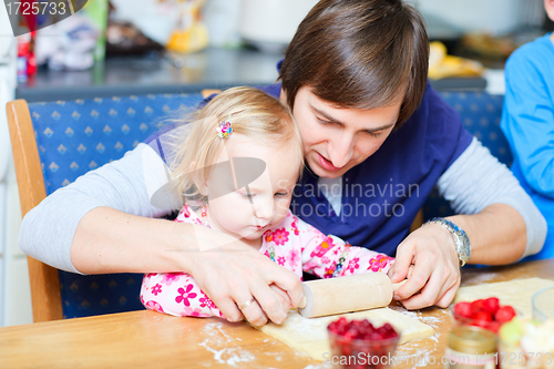 Image of Toddler girl and her dad baking pie