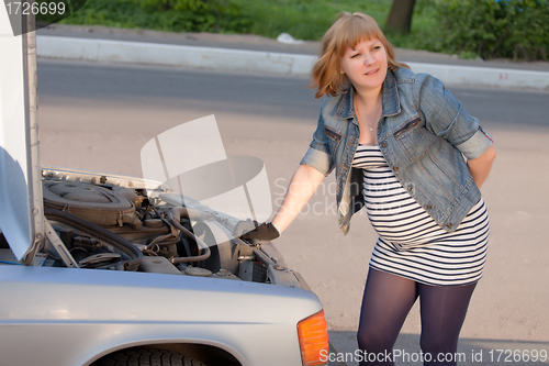 Image of Pregnant Woman Trying to Repair the Car