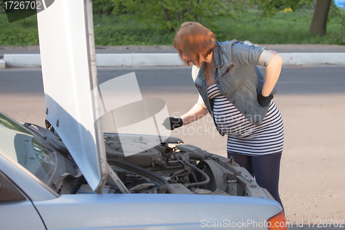 Image of Pregnant Woman Trying to Repair the Car