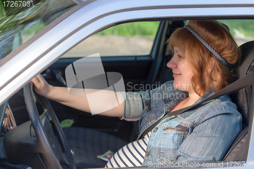 Image of Pregnant woman fastening seat belt in the car