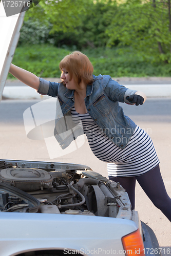 Image of Pregnant Woman Opens the Hood of the Car