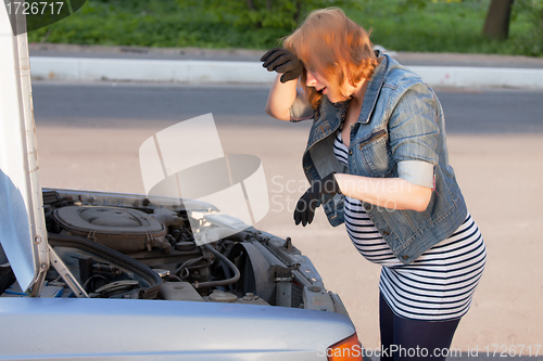 Image of Pregnant Woman Trying to Repair the Car