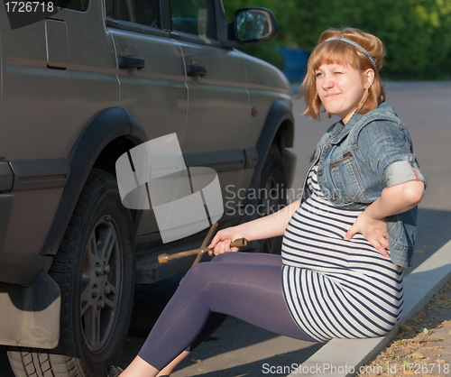 Image of Pregnant Woman with a Wheel Brace near Car