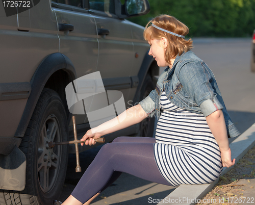 Image of Pregnant Woman with a Wheel Brace near Car