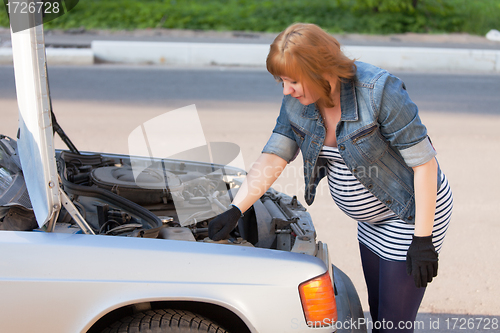 Image of Pregnant Woman Trying to Repair the Car