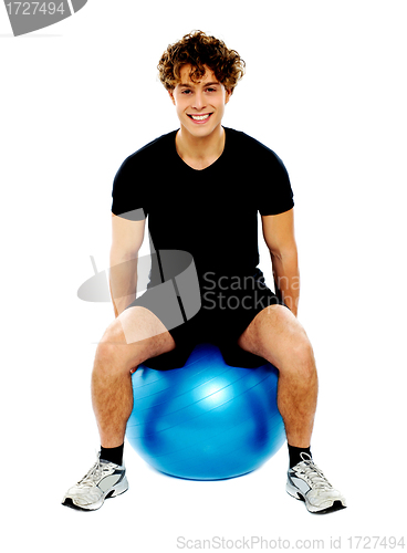 Image of Handsome guy seated on exercise ball