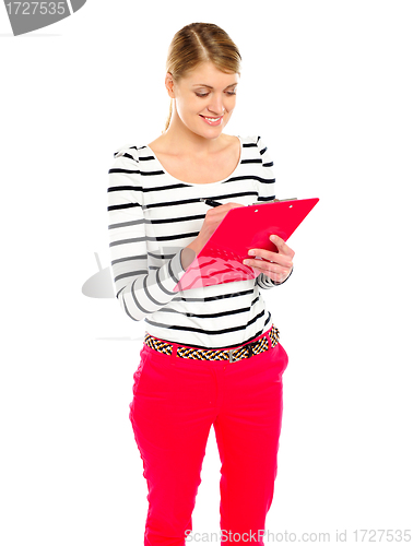 Image of Young girl writing makes notes on clipboard