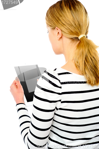 Image of Rear view of teenage girl using touch screen device