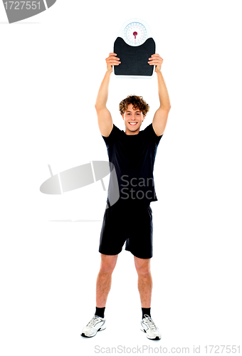 Image of Male athlete holding weighing machine over his head