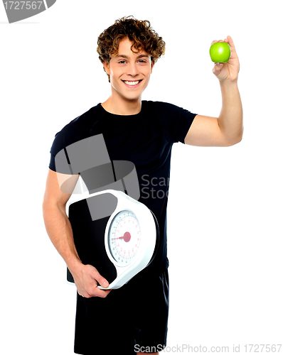 Image of Fit guy with weighing scale and green apple