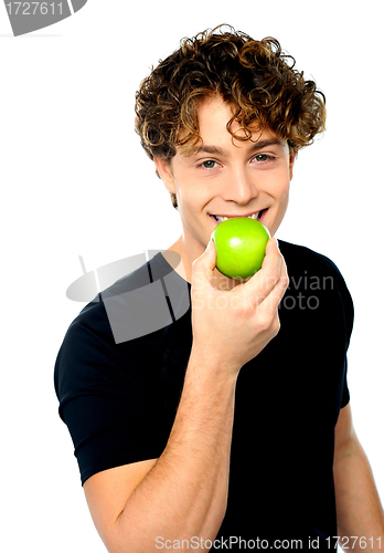 Image of Young man eating fresh healthy green apple