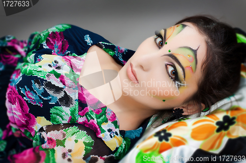 Image of young happy girl lying with beautiful make up on her face