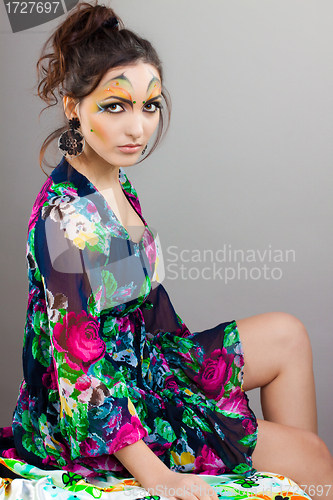 Image of beautiful girl sitting on table with professional make up