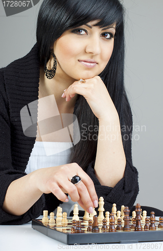 Image of A beautiful young brunette woman playing chess at home