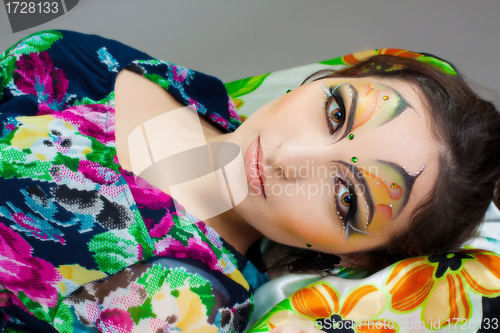 Image of young girl lying with beautiful make up on her face