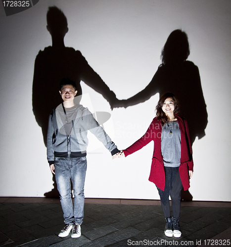 Image of Asian stylish couple on street holding hands