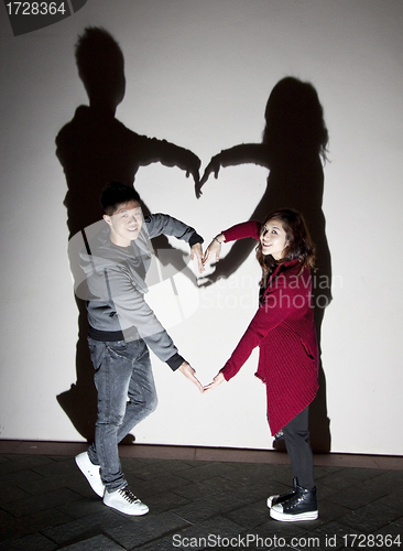 Image of Asian couple on street making a heart