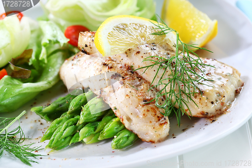 Image of Fried fish on green asparagus with salad