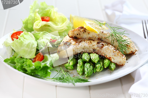 Image of Fried fish on green asparagus with salad